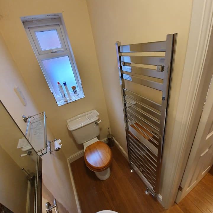 silver vertical radiator installed in a bathroom